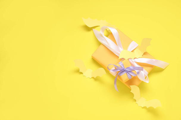 Samenstelling met mooie geschenkdozen en vleermuizen van papier voor Halloween op gele achtergrond - Foto, afbeelding
