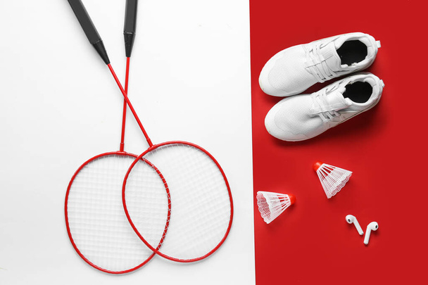 Par de tênis, raquetes de badminton, shuttlecocks e fones de ouvido no fundo de cor - Foto, Imagem