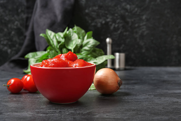 Cuenco de tomates enlatados y cebolla sobre fondo oscuro - Foto, imagen