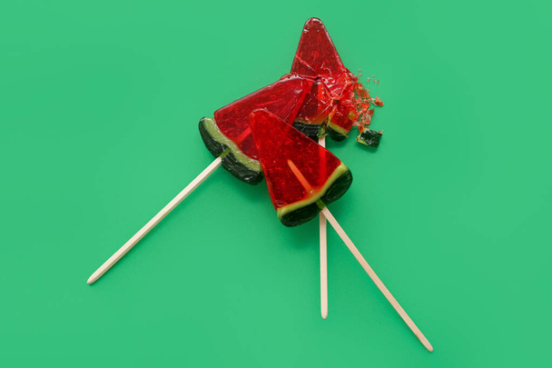 Lollipops in shape of watermelon slice on green background - 写真・画像