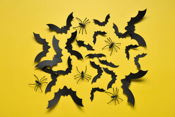 Papieren vleermuizen en spinnen voor Halloween feest op gele achtergrond - Foto, afbeelding