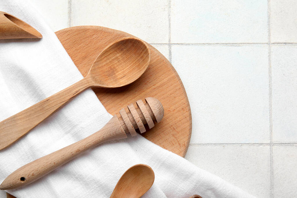 Композиція з дерев'яним кухонним начинням і серветкою на фоні легкої плитки - Фото, зображення