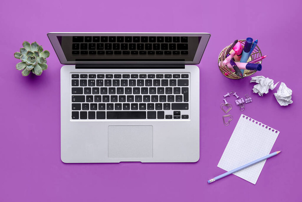 Modern laptop and different stationery on purple background - Фото, зображення