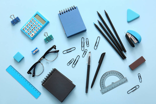 Diferentes artigos de papelaria escolar, cadernos e óculos em fundo azul - Foto, Imagem