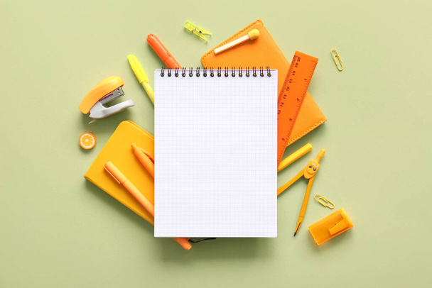 Composition with blank notebook and different school stationery on green background - Фото, изображение