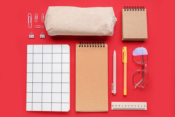 Composition with different stationery and eyeglasses on red background - Valokuva, kuva