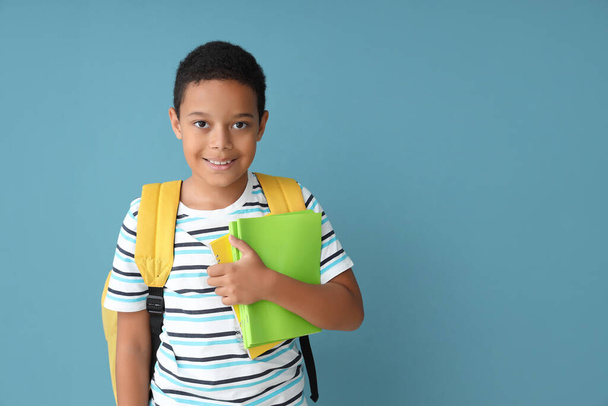 Little African-American boy with school backpack and copybooks on blue background - Photo, image