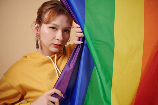 Портрет транссексуальної жінки, що стоїть під смугастим прапором - Фото, зображення