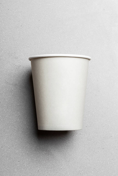 Una taza blanca para llevar colocada en su lado, creando una apariencia casual y relajada. - Foto, imagen