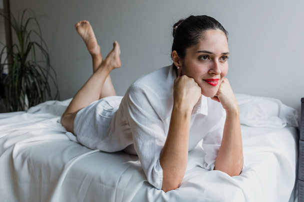 Retrato de mujer latina madura relajándose en la cama riendo en casa en México América Latina, mujer hispana - Foto, Imagen