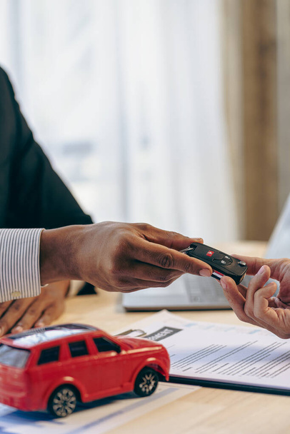 The car dealership office calculates the interest rate and the cost of a car loan. Providing financial and insurance services while the customer reads the terms and conditions of the contract - Valokuva, kuva