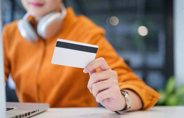 Mujer feliz sosteniendo la tarjeta de crédito en su mano. Compras en línea, concepto de comercio electrónico. - Foto, Imagen