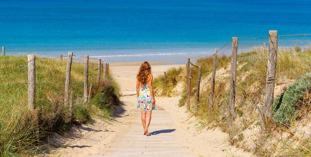 Woman walking on wooden path to the beach - Foto, Imagem