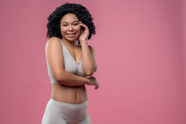 Woman in lingerie. Curly-haired young woman in lingerie on pink background - Fotografie, Obrázek