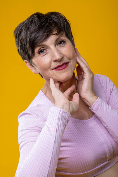 Smiling woman. Short-haired senior smiling woman in pink - Foto, afbeelding
