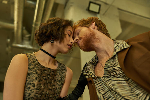 niski kąt widzenia stylowe międzyrasowe para całowanie w publiczne pralnia wieczorem - Zdjęcie, obraz