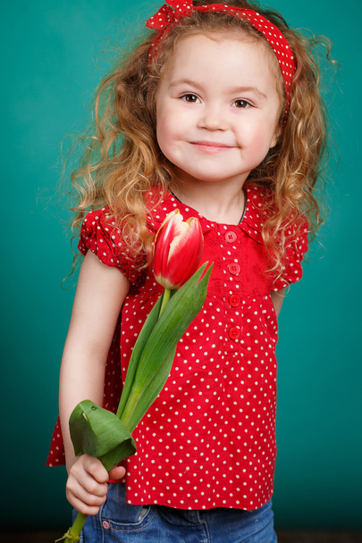 Beautiful little girl with a big bouquet of tulips. - 写真・画像