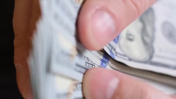 Közelkép a férfi kezekről, amint százdollárosokat számolnak. Befektetés, vesztegetés vagy korrupció. Szelektív fókusz. Függőleges videó - Felvétel, videó