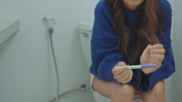 Stressaamaton nainen istuu wc ja odottaa raskaustestin tulokset. - Materiaali, video
