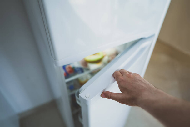 El hombre abre la puerta del refrigerador con la comida. - Foto, imagen