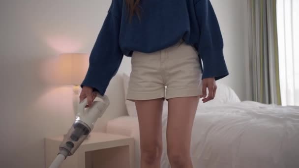 Jonge vrouw die vloer schoonmaakt met accustofzuiger in moderne witte woonkamer. - Video