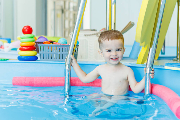 Ein 2-jähriger kleiner Junge lernt in einem sauberen Pool schwimmen. Entwicklung von Kindern. Entwicklungspool, um Kindern Schwimmen beizubringen. Schwimmschule - Foto, Bild