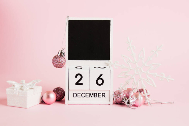Christmas and Boxing Day, wooden calendar with December 26 date and Christmas tree decorations on pink background. Christmas and New Year celebration concept - Photo, image