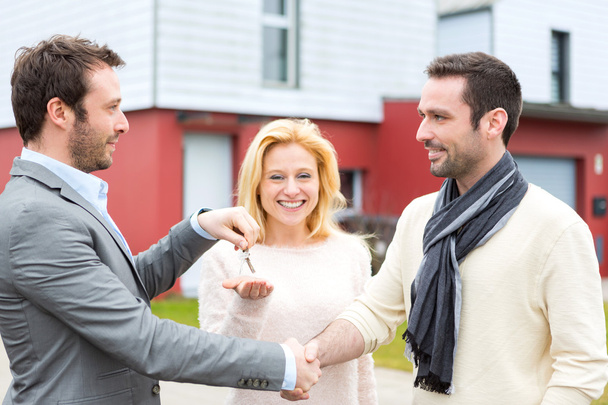 Real estate agent delivers keys to young atractive couple - Photo, Image