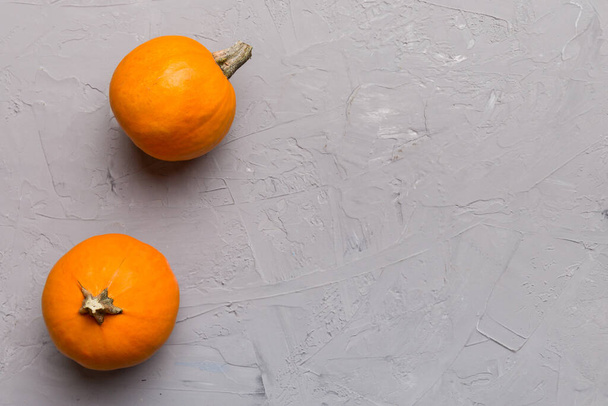 Jesienna kompozycja małych pomarańczowych dyń na kolorowym tle stołu. Jesień, Halloween i pomysł na Święto Dziękczynienia. Jesienna płaska fotografia. Przestrzeń kopiowania w widoku góry. - Zdjęcie, obraz