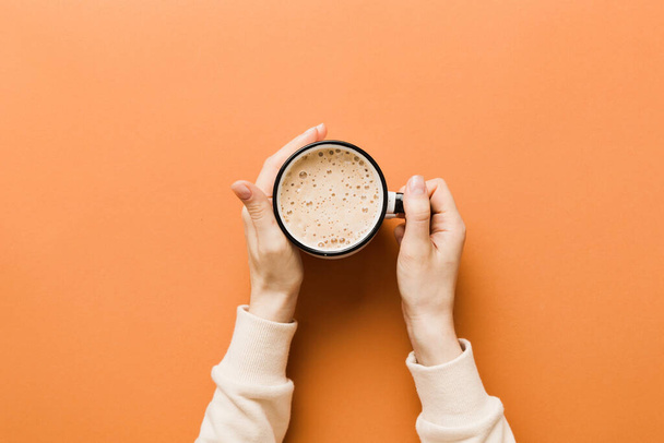 Renkli arka planda bir fincan kahve tutan minimalist stil bir kadın. Düz yerde, kapuçino bardağının üstünde. Metin için boş yer, kopyalama alanı. Kahve bağımlılığı. Üst manzara, düz uzanma. - Fotoğraf, Görsel