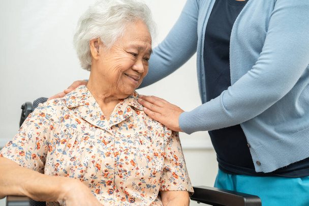 Caregiver help Asian elderly woman patient with love, care, encourage and empathy at nursing hospital, healthy strong medical concept. - Photo, Image