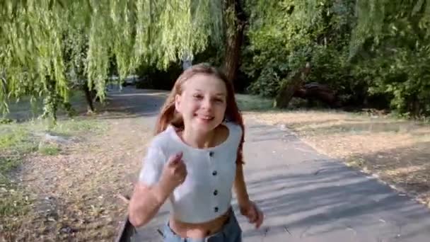 Radosna uczennica szkoły biegnie przez park ze szczerym uśmiechem na twarzy, jest na wakacjach. - Materiał filmowy, wideo