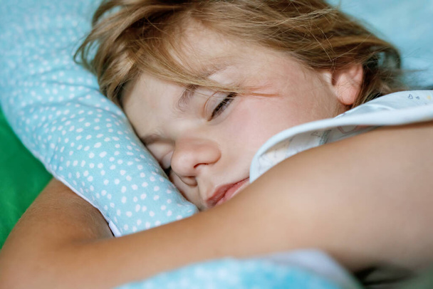 かわいい就学前の女の子がベッドで寝ています。愛らしい就学前の子供は毎日子供の健康的な睡眠を夢見ています。幼児の深い眠り。休みの子供たち - 写真・画像