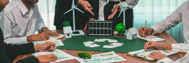 Vihreän energian yritys tapaa yrittäjiä, jotka suunnittelevat ja keskustelevat kestävän ja uusiutuvan puhtaan energiatuotteen markkinoinnista aurinkokenno- ja tuulivoimageneraattorin kanssa. Tiennäyttäjä - Valokuva, kuva
