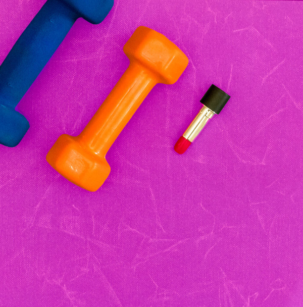 Dumbbells and lipstick over pink background with copy space - Photo, Image