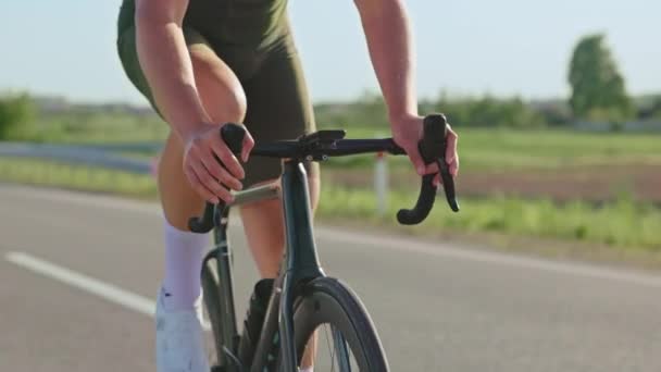 Gesneden weergave van mannelijke sporter controleren van gegevens op de fiets computer tijdens het fietsen racefiets op de weg land. Fit active rider test gespierd uithoudingsvermogen tijdens intensieve training buiten. - Video