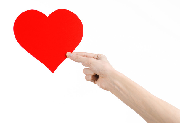 Valentine's Day and love theme: hand holding a red heart isolated on a white background in studio - 写真・画像