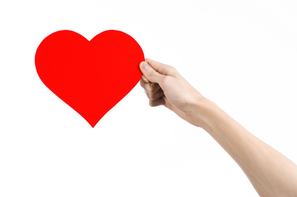 Valentine's Day and love theme: hand holding a red heart isolated on a white background in studio - Photo, image