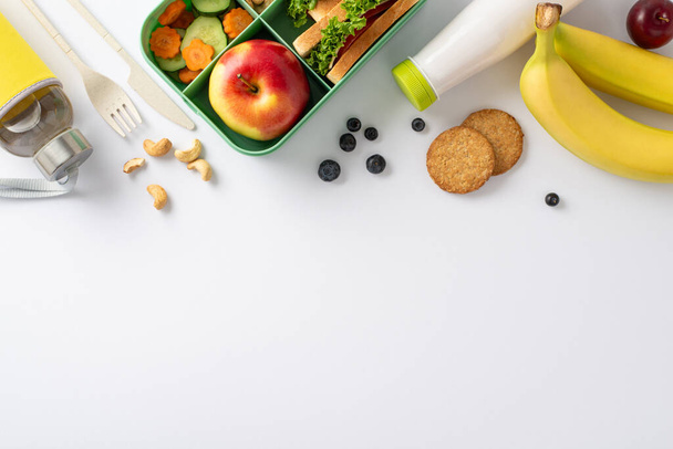 An inviting and nutritious school break arrangement displayed from a bird's eye top view. A lunchbox containing delicious sandwiches set against a white backdrop with space for text or advertising - Photo, Image