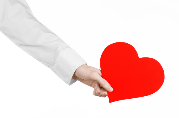 Onemocnění srdce a zdraví téma: rukou lékaře v bílé košili drží karty v podobě červené srdce izolovaných na bílém pozadí v studio - Fotografie, Obrázek