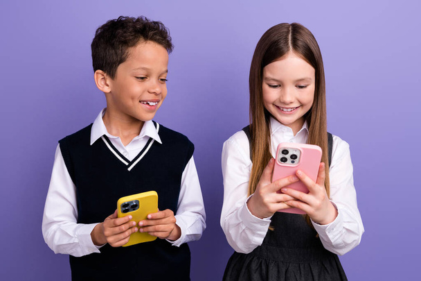 Photo of school kids using cell smart gadget watch learn video on youtube network isolated purple color background. - Фото, изображение