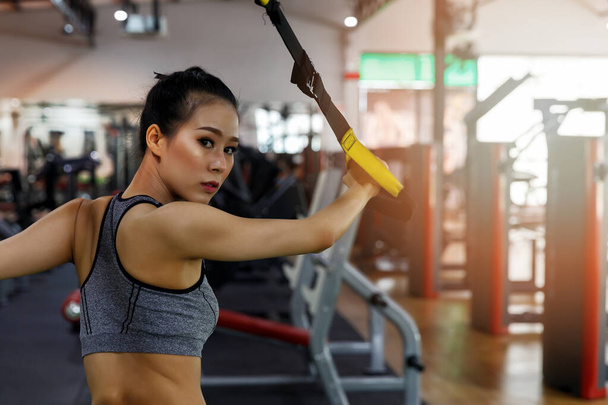 Fitness woman training with trx fitness straps in gym. Healthy lifestyle concept. - Zdjęcie, obraz