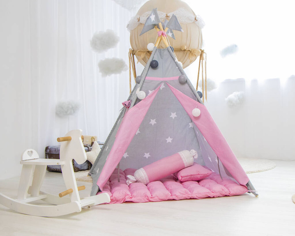 Sala giochi con Teepee. Camera moderna con tenda da gioco per bambini. wigwam rosa per bambini nella stanza sul pavimento in stile scandinavo con arredamento. Foto di alta qualità - Foto, immagini