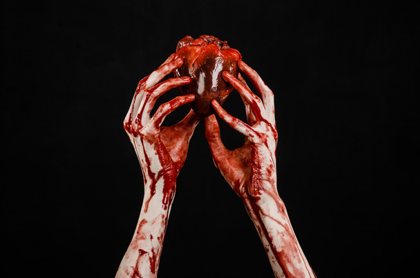 Blood and Halloween theme: terrible bloody hand hold torn bleeding human heart isolated on black background in studio - Zdjęcie, obraz