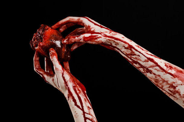 Blood and Halloween theme: terrible bloody hand hold torn bleeding human heart isolated on black background in studio - Foto, Imagem
