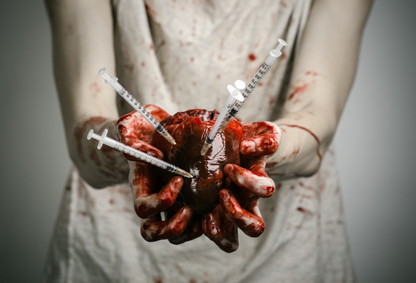 Social advertising and the fight against drug addiction: bloody hands addict holding syringe and bloody human heart - 写真・画像