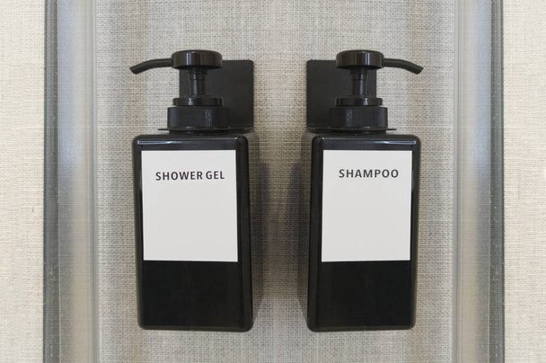 Gel líquido e dispensadores de shampoo ligados à parede do chuveiro. Foco seletivo - Foto, Imagem