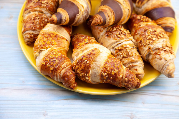Chocolate croissants or croissant with nut crumbs on a plate. Delicious breakfast on the table. Tasty sweet baking dessert for coffee. Food background. Fresh buttery croissants rolls - Foto, immagini