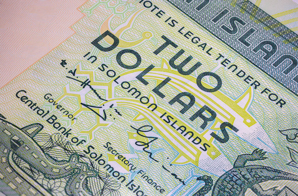 2 доларові банкноти Соломонових Островів мають вигадливе художнє оформлення та дизайн. крупним планом розкриває яскраві кольори, мотиви корінних народів та портрет видатної історичної фігури, мистецтва грошей - Фото, зображення