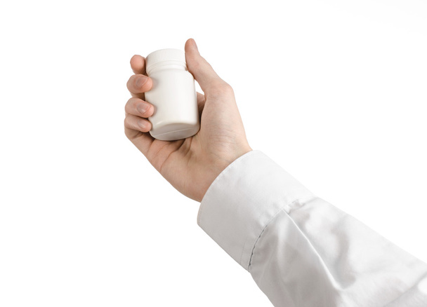 Lékařská téma: za ruku drží bílé prázdné sklenice prášků na bílém pozadí - Fotografie, Obrázek